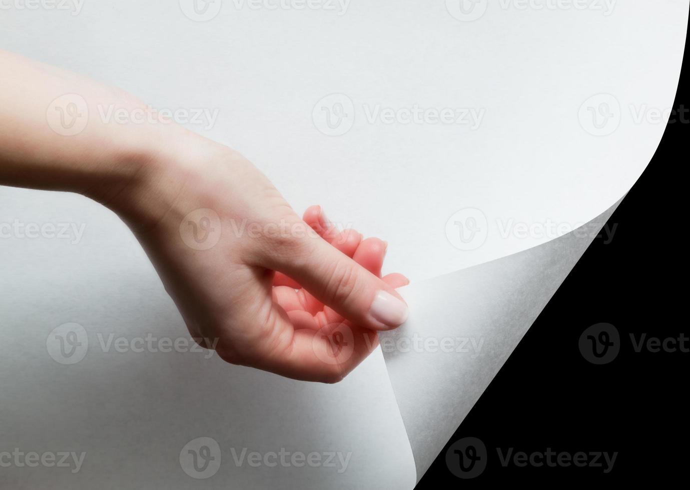 Hand pulling a paper corner to uncover, reveal something photo