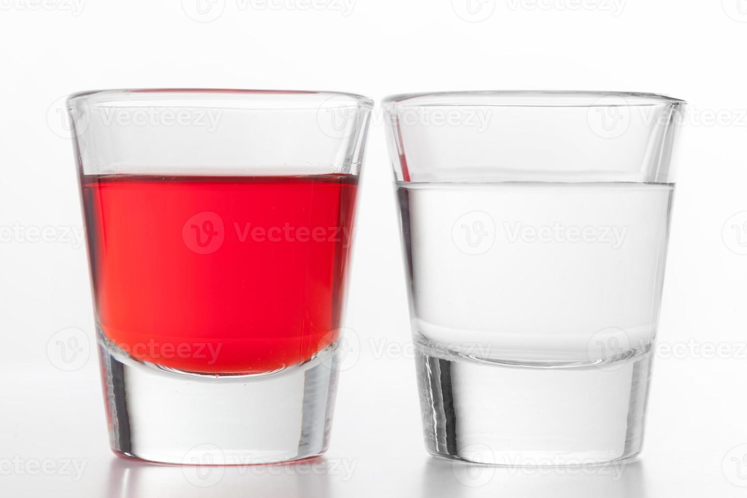 dos vasos de alcohol. uno rojo con sabor, el otro vodka limpio. foto