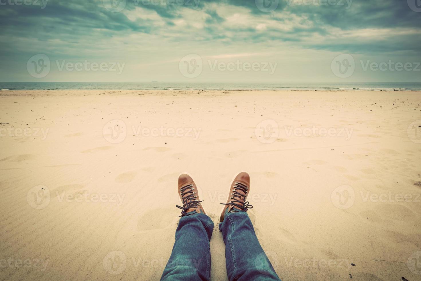 First person perspective of man legs in jeans on the autumn beach photo