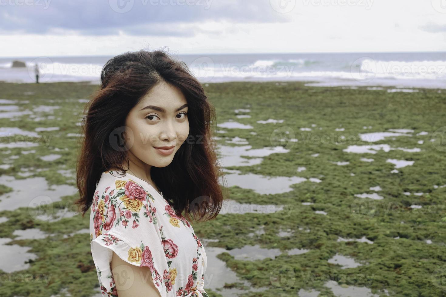 una joven asiática en la playa sonríe a la cámara en gunungkidul, indonesia foto