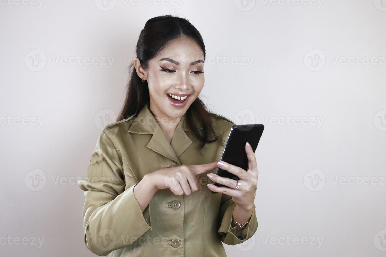 Smiling government worker women holding and pointing screen on smartphone. PNS wearing khaki uniform. photo