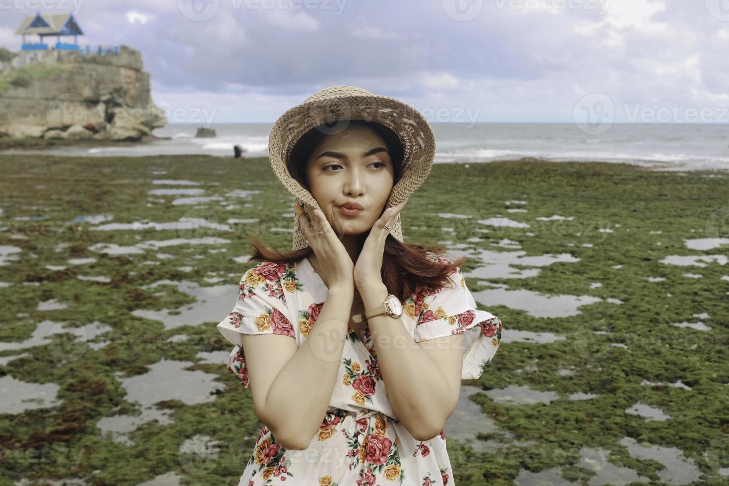 una joven y linda chica asiática que lleva un sombrero para el sol se relaja en la playa del cielo azul en gunungkidul, indonesia foto