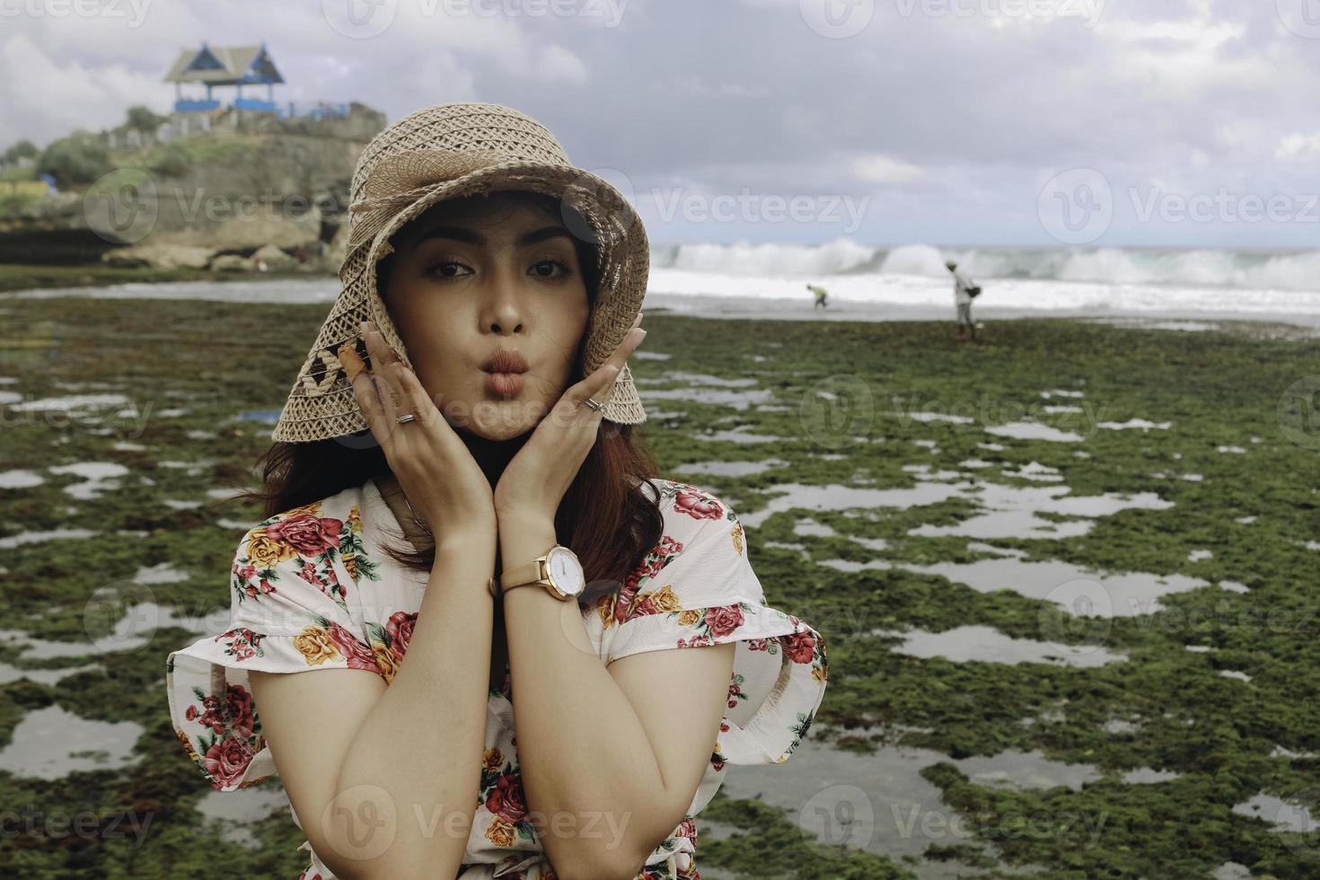 A young Asian girl wearing a beach hat is relaxing on the blue sky beach at Gunungkidul, Indonesia photo