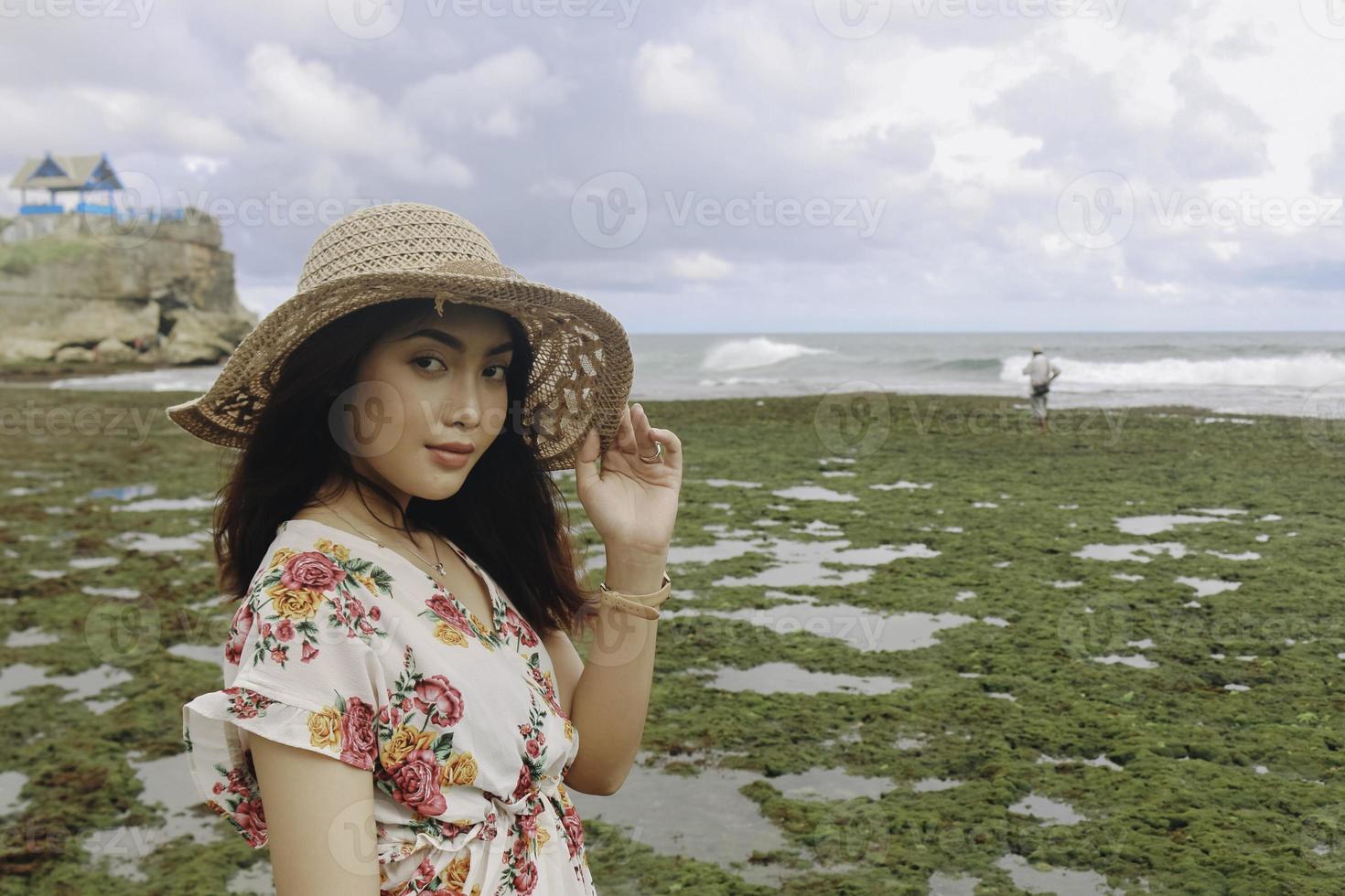 A young Asian girl wearing a beach hat is relaxing on the blue sky beach at Gunungkidul, Indonesia photo