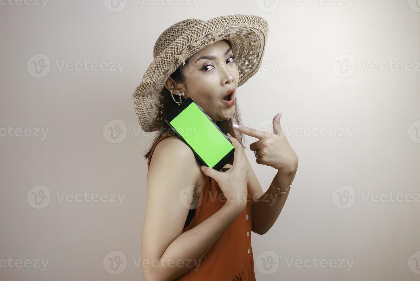 Excited and shocked Asian woman showing screen at smartphone in her hand. photo