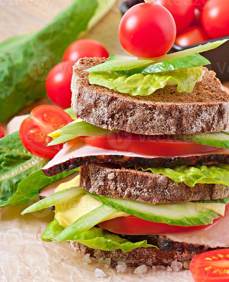 Sandwich with ham and fresh vegetables on a wooden background photo