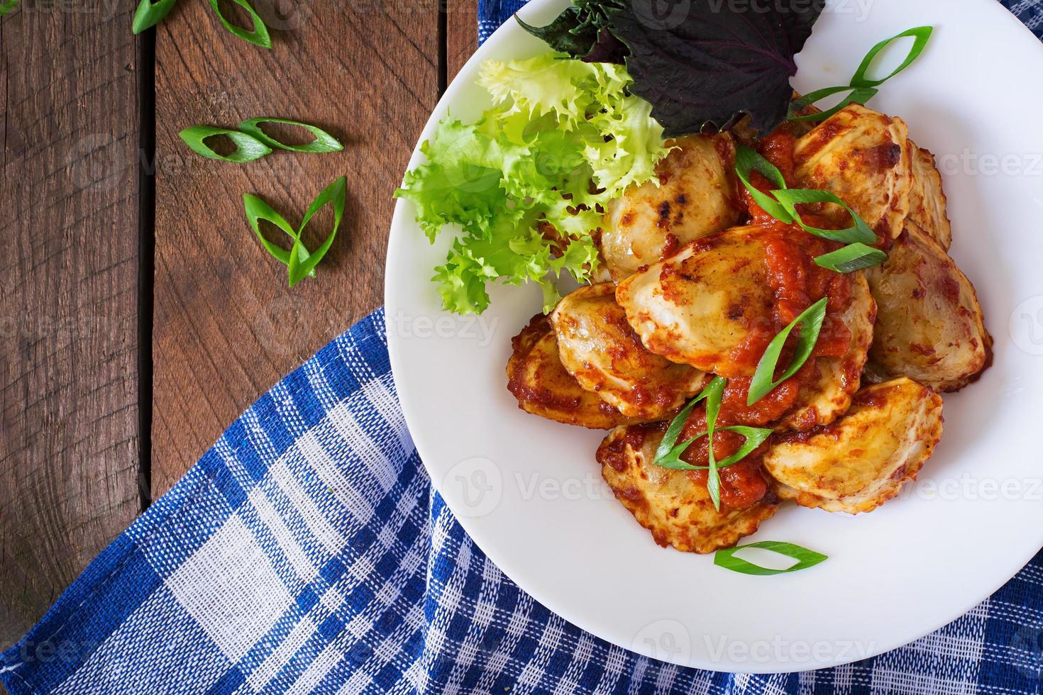 Delicious ravioli with tomato sauce and green onions photo