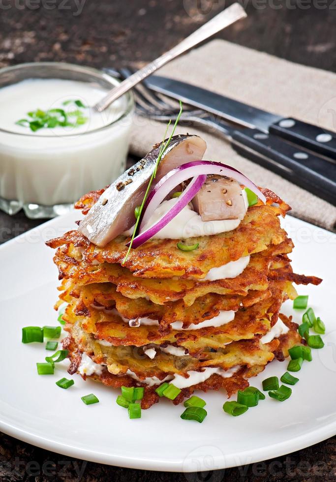 tortitas de patata frita con arenque en el antiguo fondo de madera foto