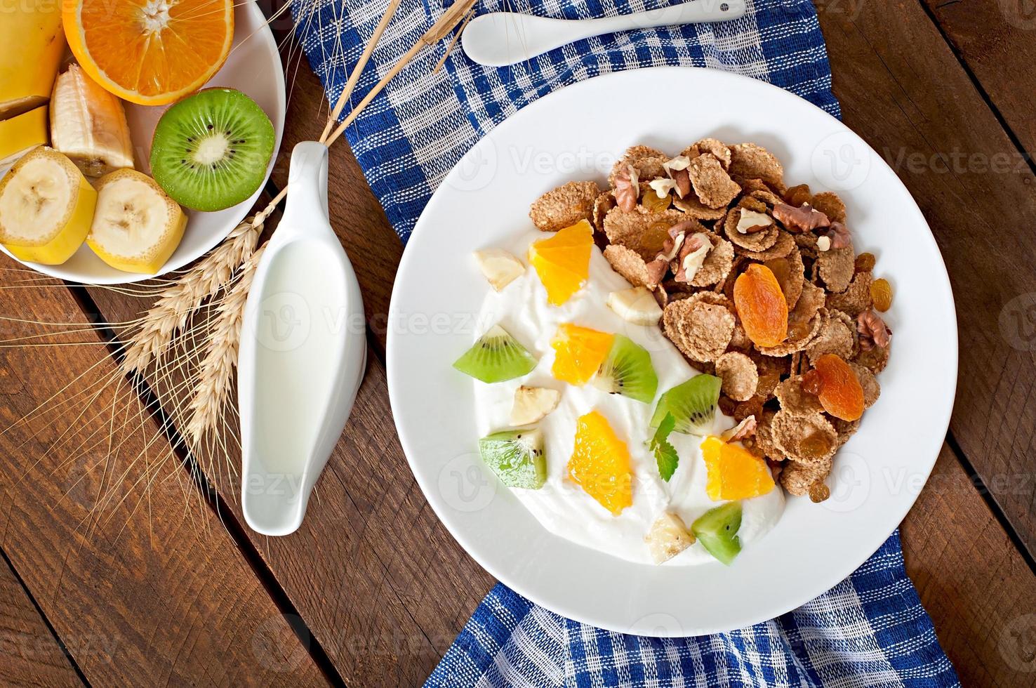 Healthy dessert with muesli and fruit in a white plate on the table photo