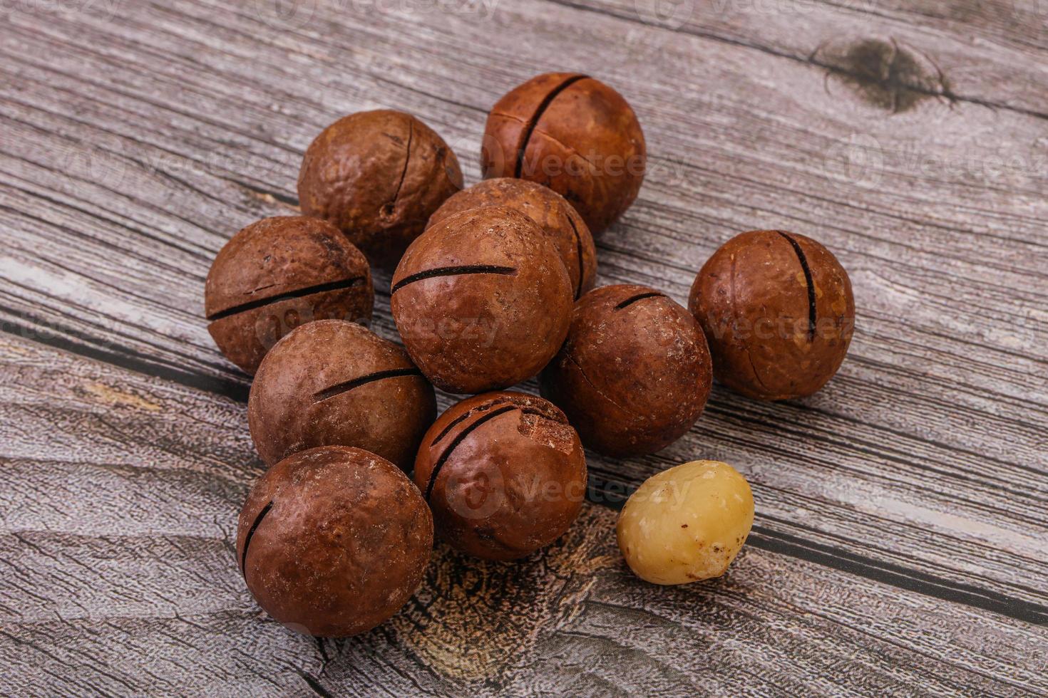 Brown macadamia nut heap over background photo