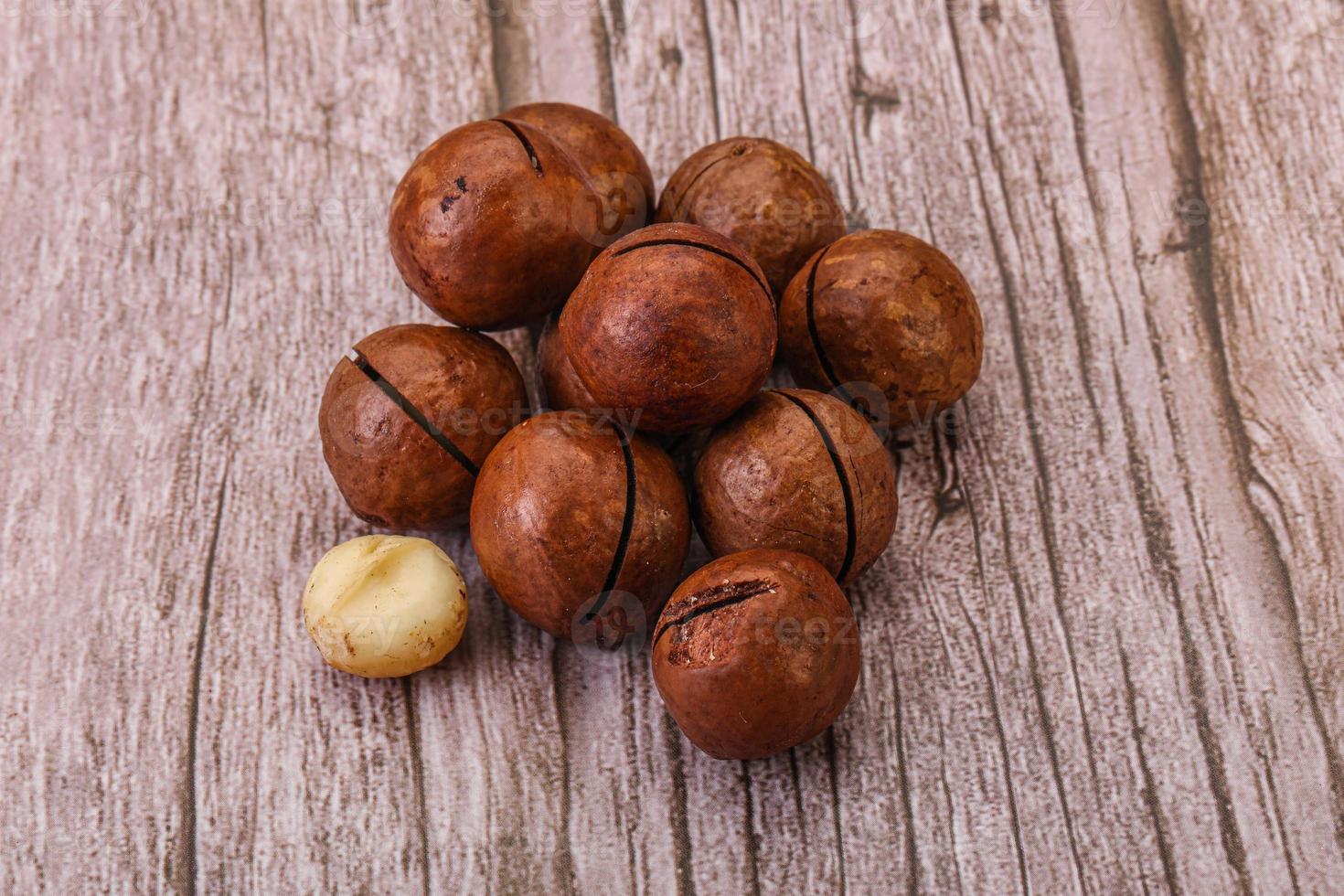 Brown macadamia nut heap over background photo