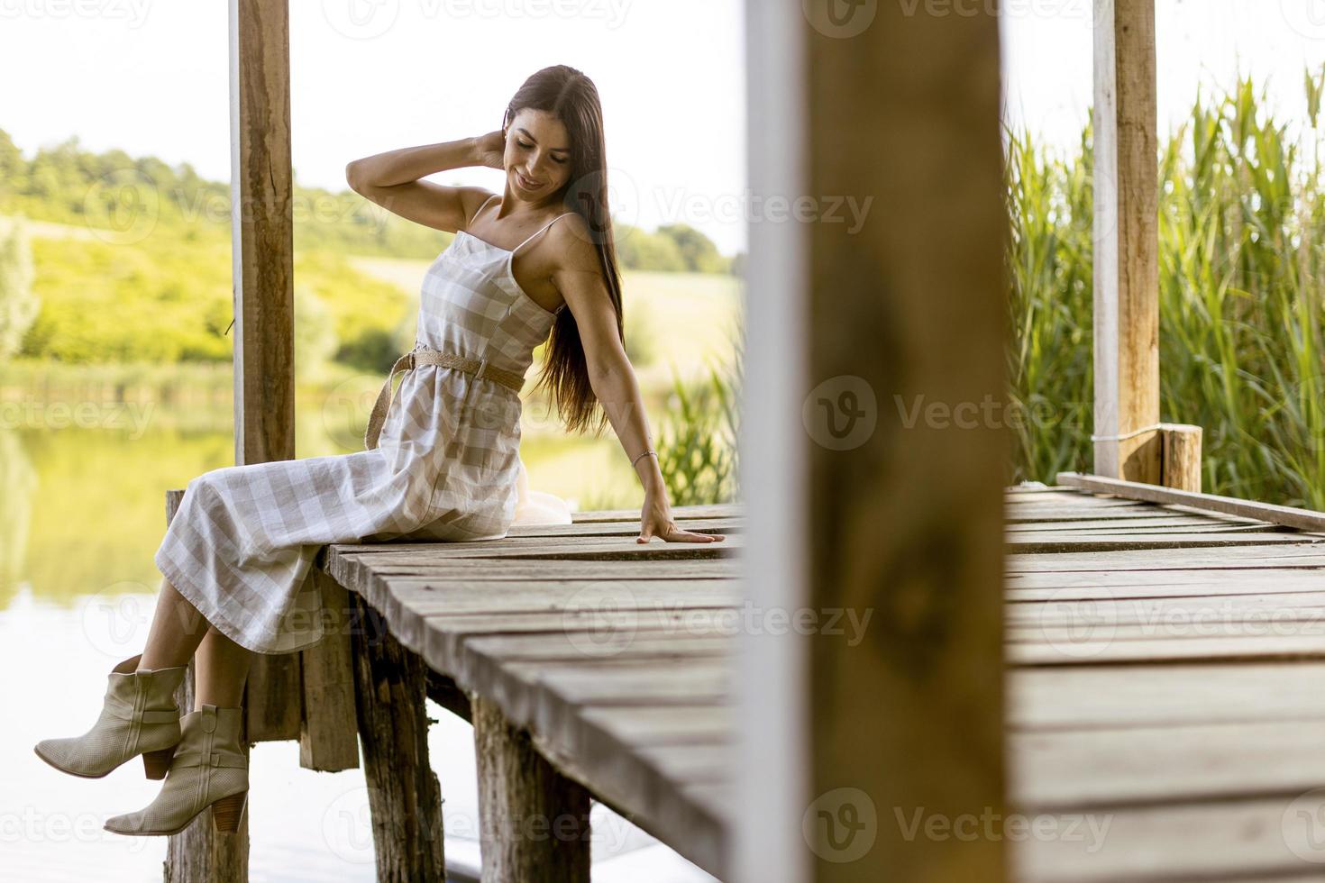 mujer joven relajándose en el muelle de madera en el lago tranquilo foto