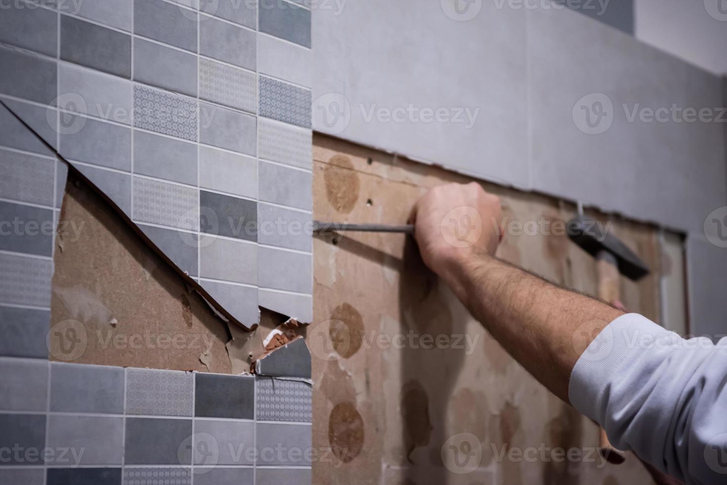 worker remove demolish old tiles in a bathroom photo