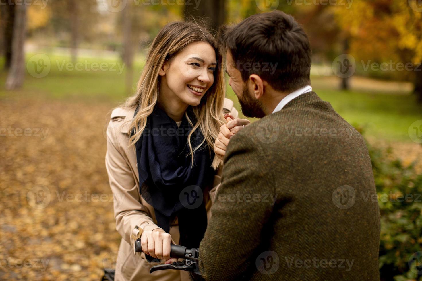 Young couple in the autumn park with electrical bicycle photo