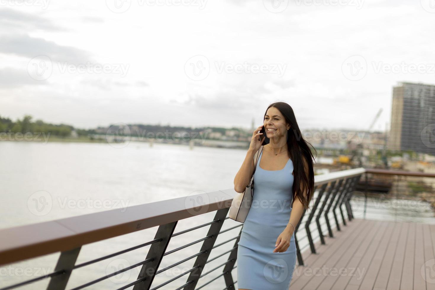 Young woman using a mobile phone while walking on the river promenade photo