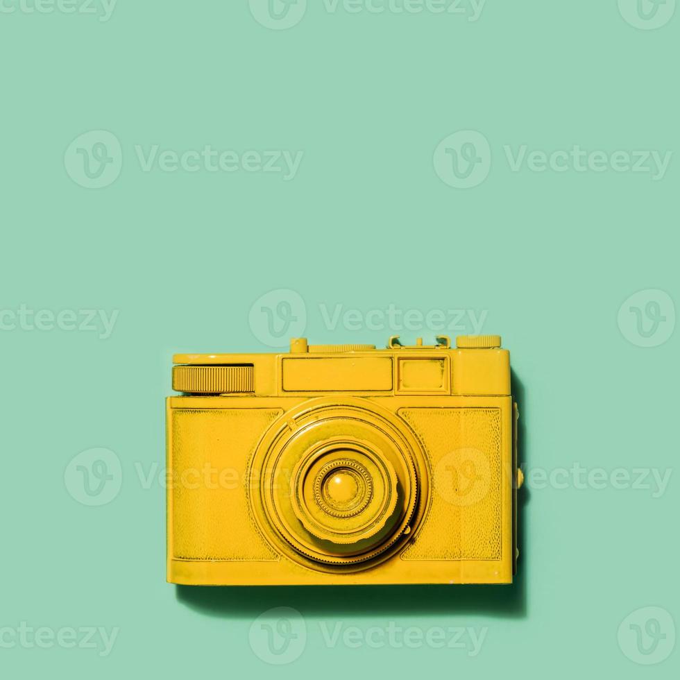 Yellow camera laying on a green background photo