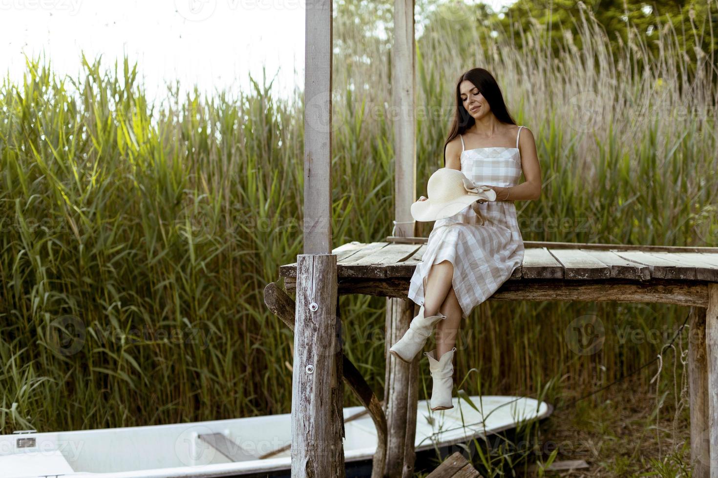 Young woman relaxing on the wooden pier at the calm lake photo