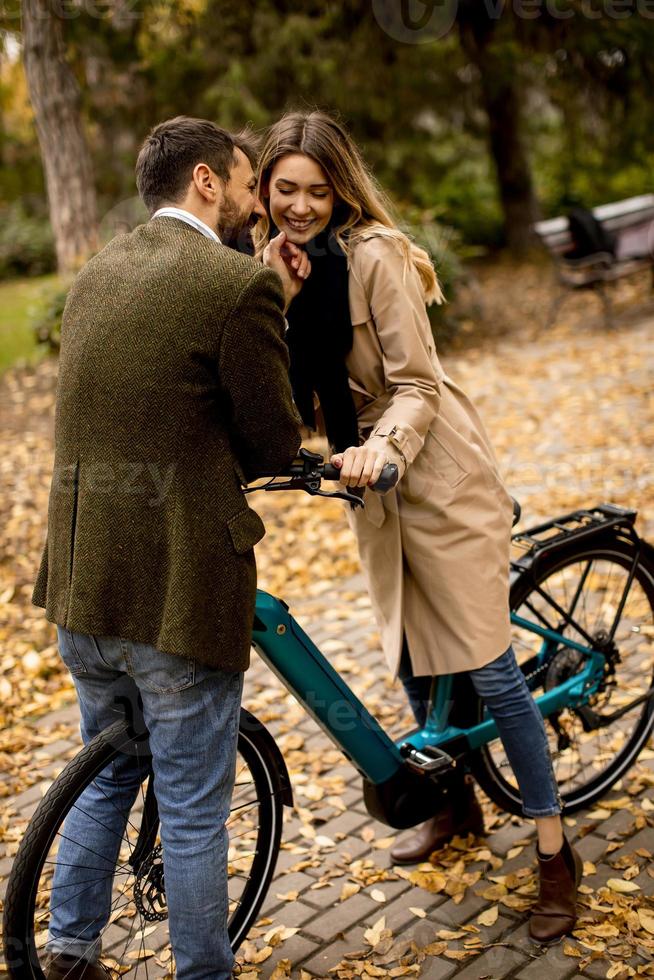 Young couple in the autumn park with electrical bicycle photo