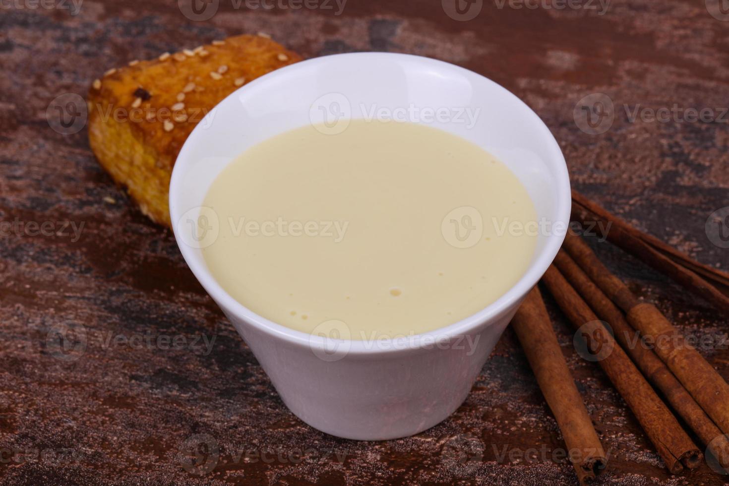Condenced milk in the bowl with sinnamon and pastry photo