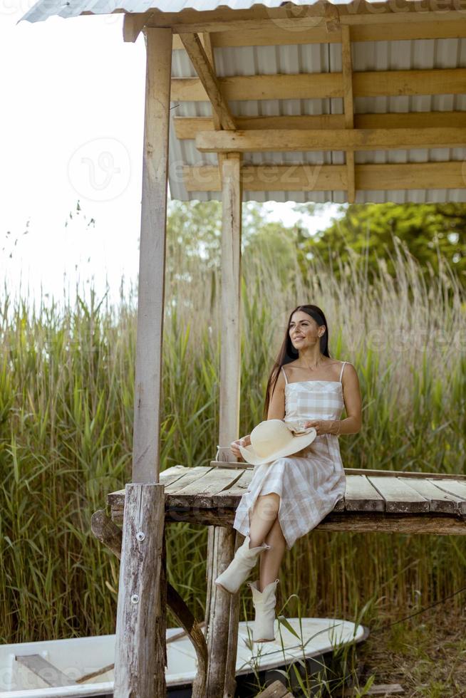 mujer joven relajándose en el muelle de madera en el lago tranquilo foto