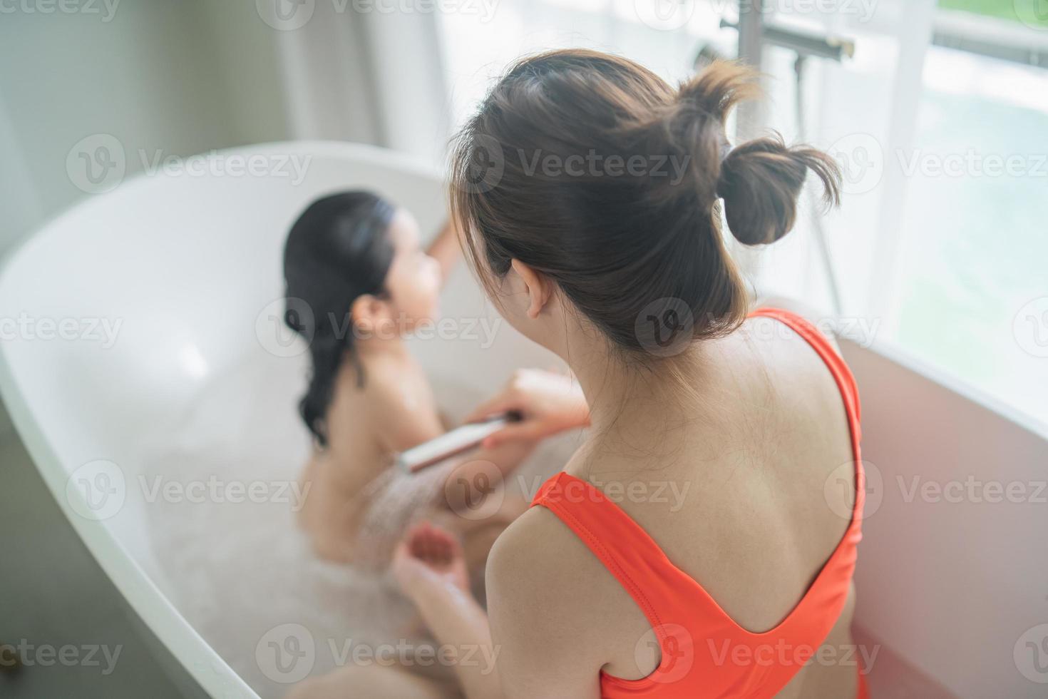 niña asiática feliz bañándose y lavándose el cabello con la madre en casa, baby shower infantil asiático. concepto de familia de bebé. foto