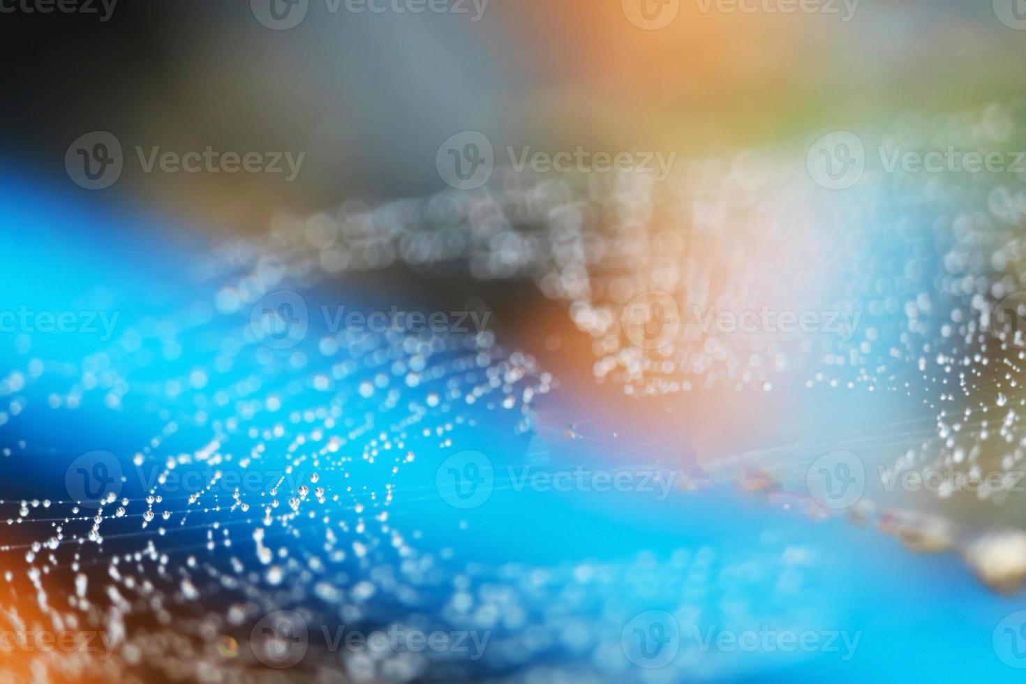 blurred abstract spiderweb natural with rain drop on the line against the sun orange blue photo