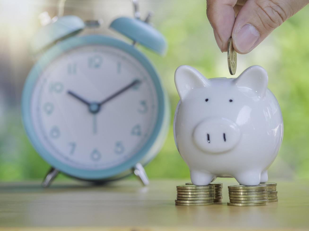 Close up hand of man is putting a coin into a piggy bank to save money invest for future. Concept for loan, property ladder, financial, real estate investment, taxes and bonus. photo