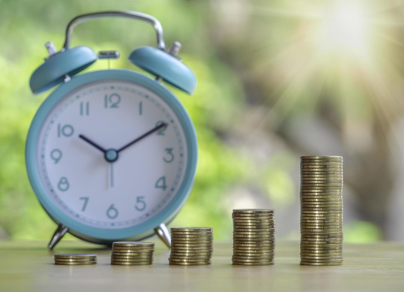 Hand are stacking coins with alarm clock to save the financial stability for the future. Concept for loan, property ladder, financial, mortgage, real estate investment, taxes and bonus. photo