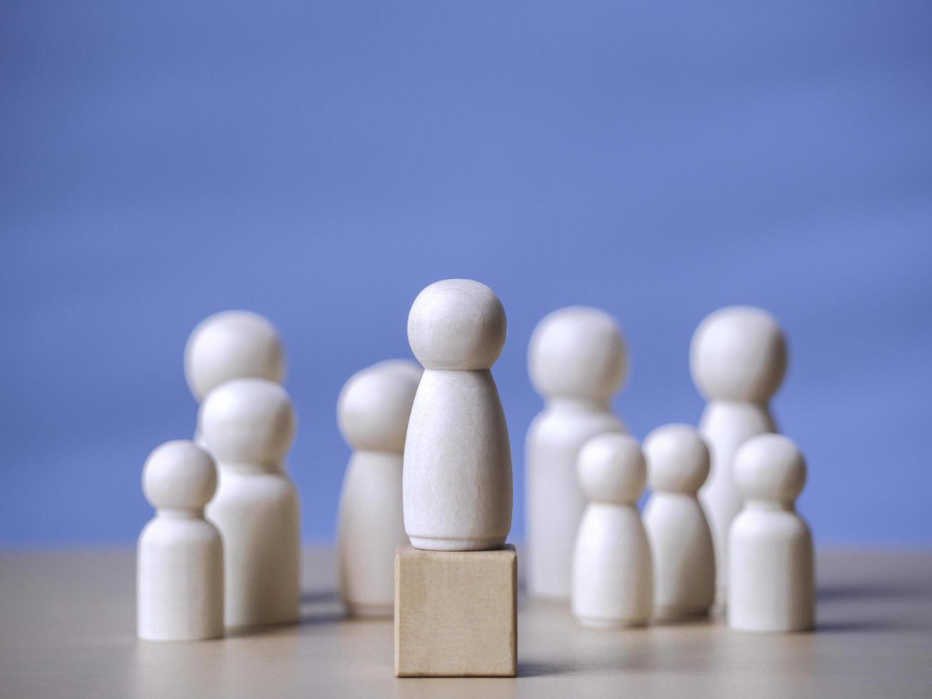 Wooden figure standing on the wooden block to talking leadingship for influence, empowerment and inspiration for crowd. Leader with influence, leader team and successful competition winner concept. photo
