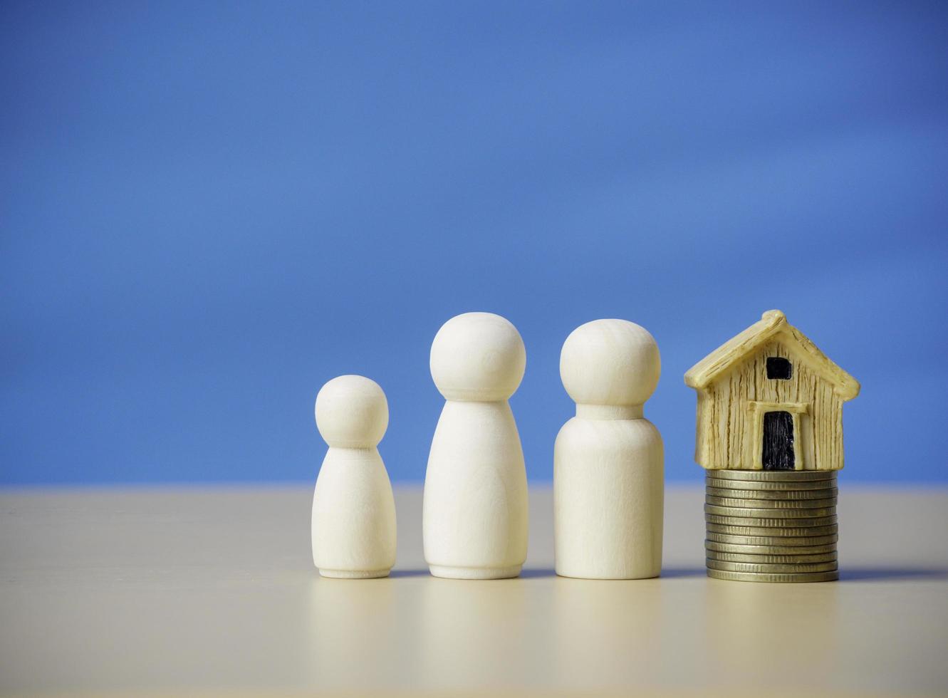 Three wooden figures people standing nearby of tiny wooden house on stack coins. Concept for family, loan, property ladder, financial, mortgage, real estate investment, taxes and bonus. photo