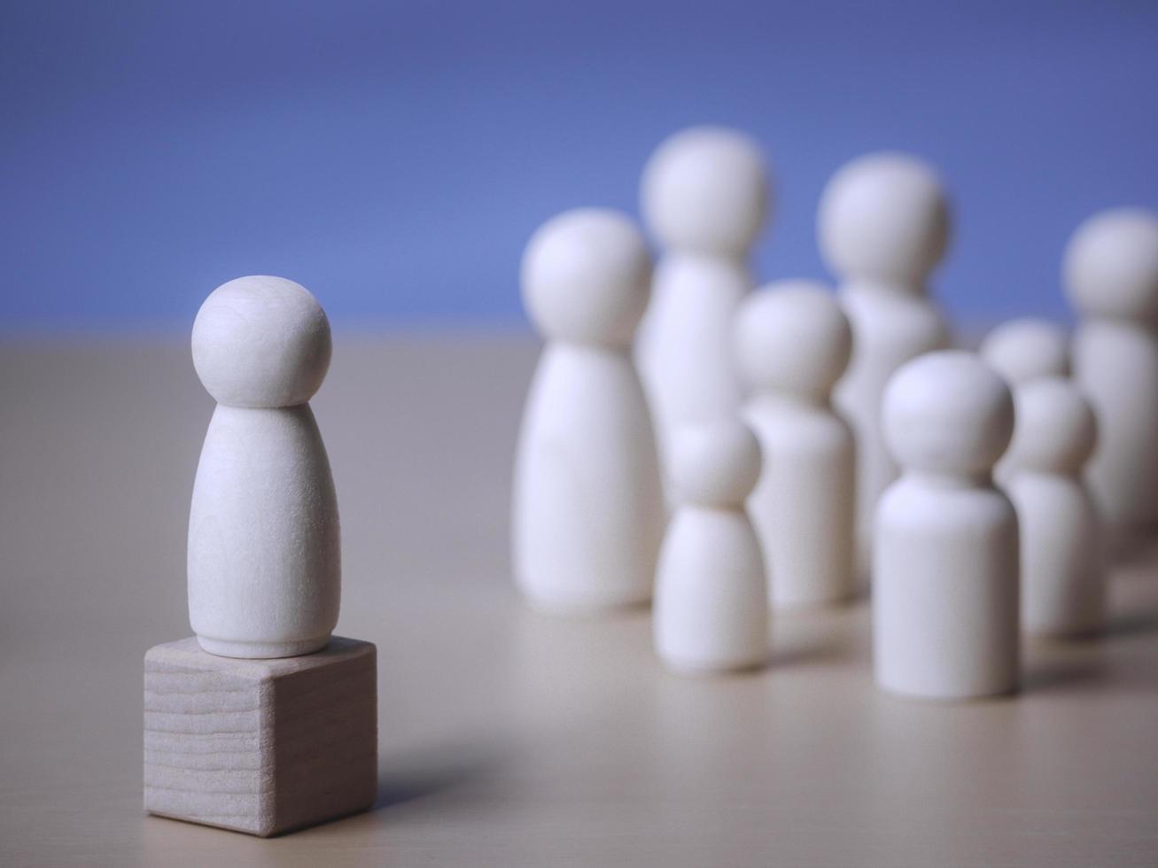 Wooden figure standing on the wooden block to talking leadingship for influence, empowerment and inspiration for crowd. Leader with influence, leader team and successful competition winner concept. photo