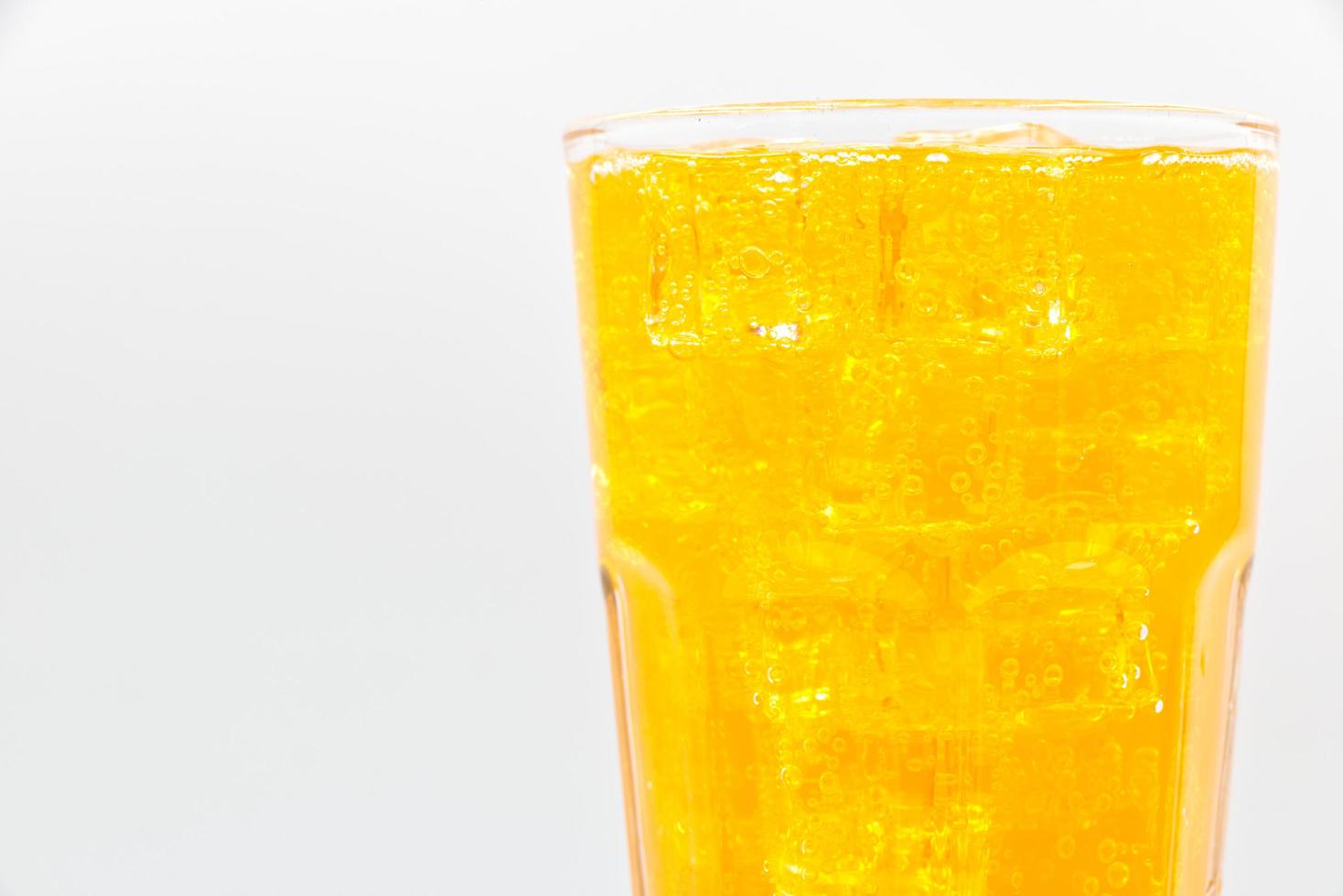 Orange sparkling water with Ice in glass over white background. photo