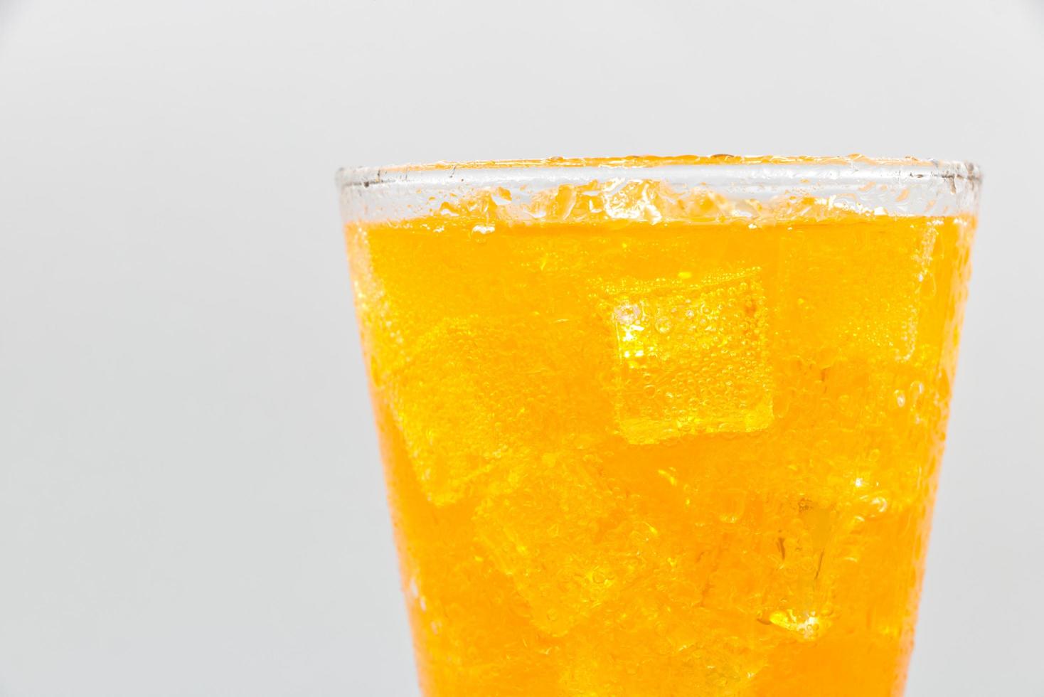 Orange sparkling water with Ice in glass over white background. photo