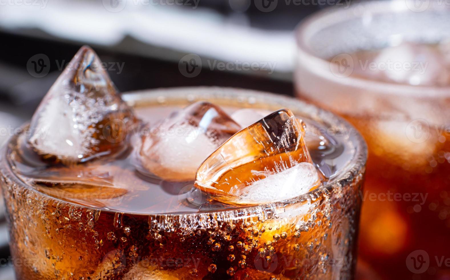 cola con hielo picado en vaso y hay gotas de agua alrededor. bebida fresca negra fresca. foto