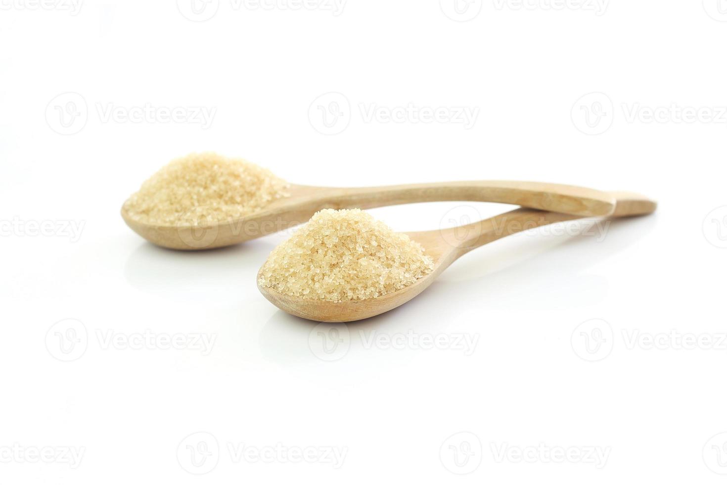 Two spoons of brown sweet granulated sugar on white background  -  selective focus photo