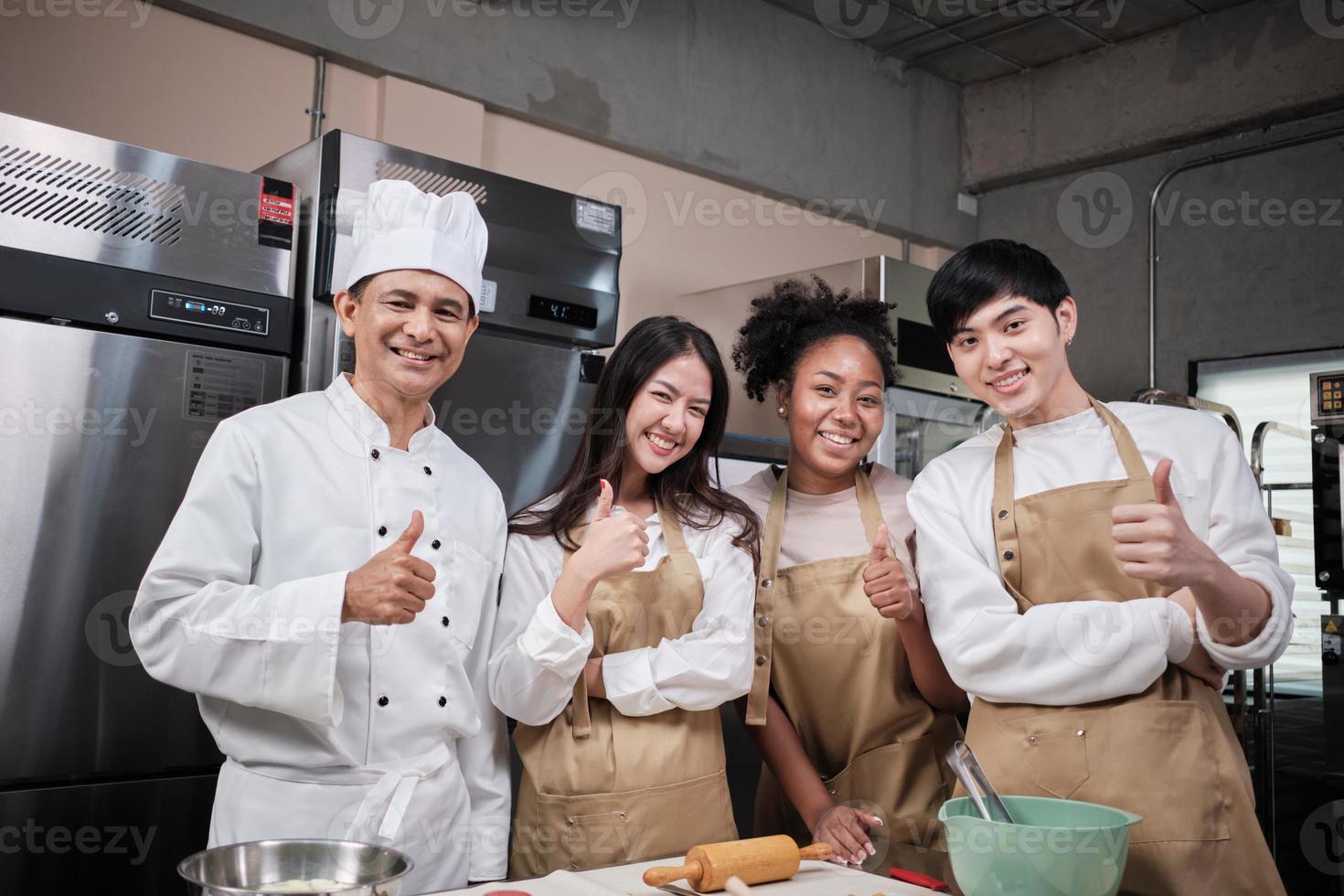 Portrait of professional cooking class people, senior male chef, and young students team looking at camera, cheerful smile and thumb up in kitchen, pastry foods and bakery course for small business. photo