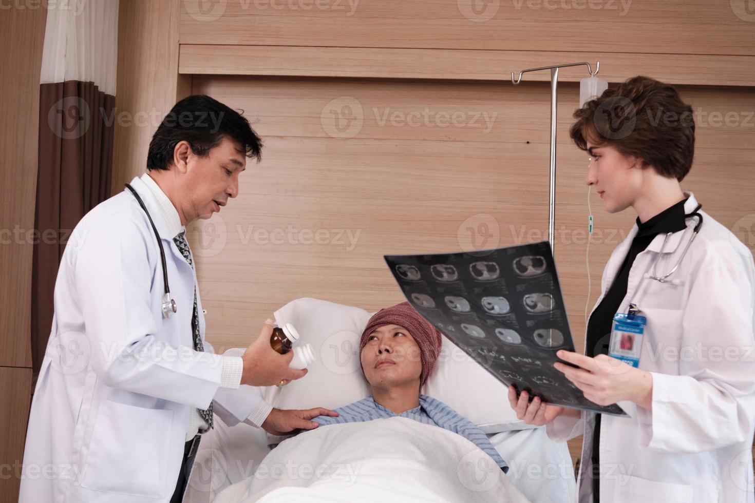 Two professional doctors team in uniform diagnosis discuss x-ray film, explain medicine to Asian recovery male patient at inpatient room in hospital ward, medical clinic, cancer examination consult. photo