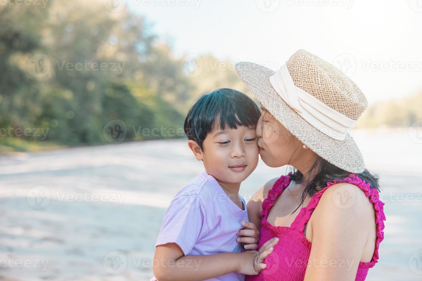 Asian boy and mom woman relaxing on tropical beach, they are njoy freedom and fresh air, wearing stylish hat and clothes. Happy smiling tourist in tropics in travel vacation photo