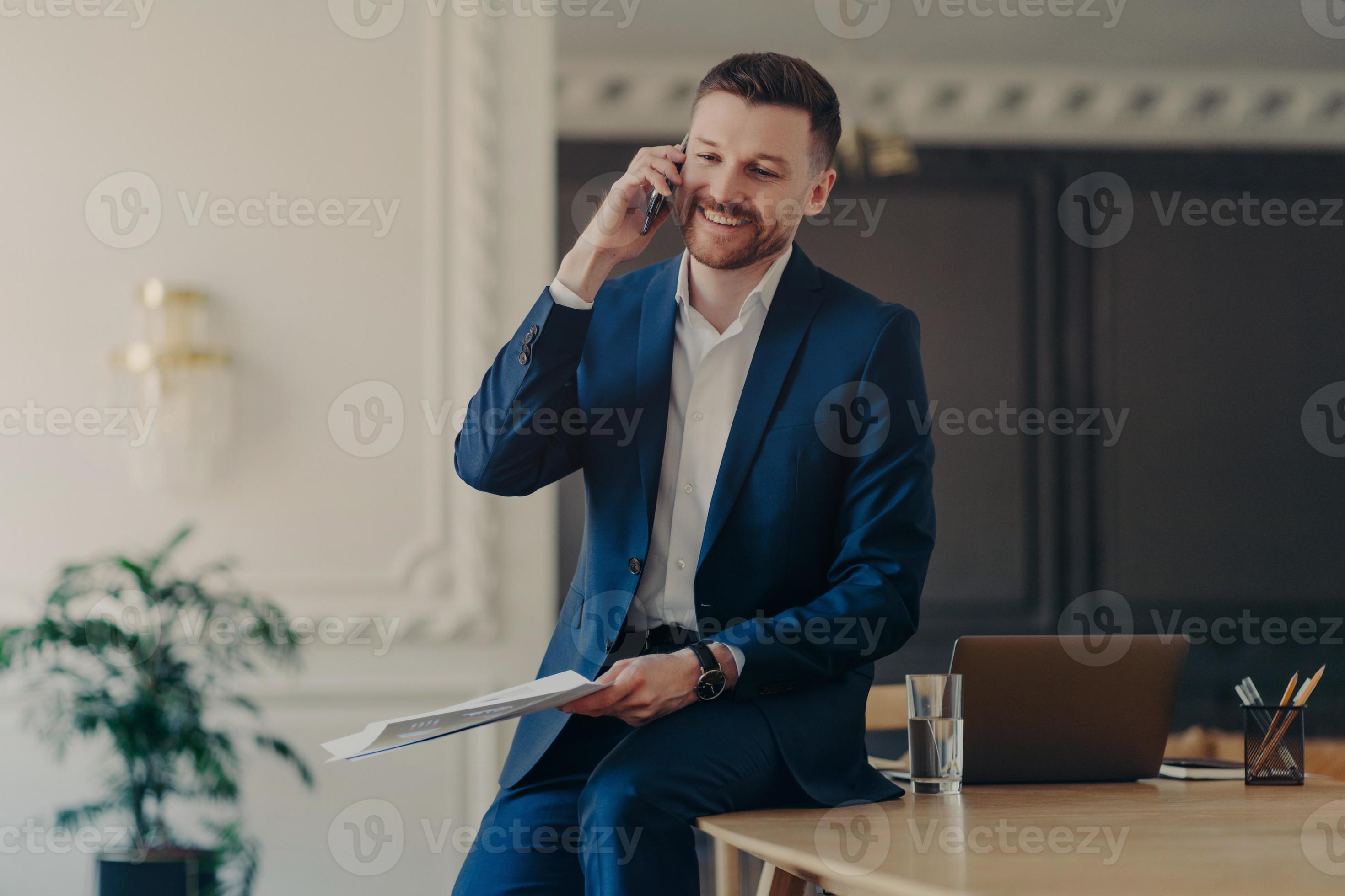 Indoor shot of positive entrepreneur dressed in formal suit has