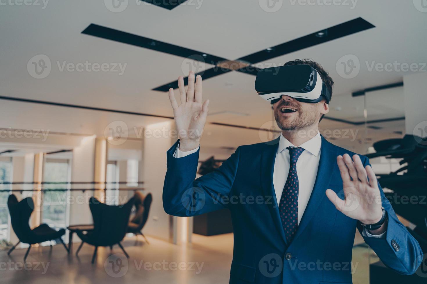 Businessman in futuristic VR headset touches air with his palms immersed in virtual reality photo