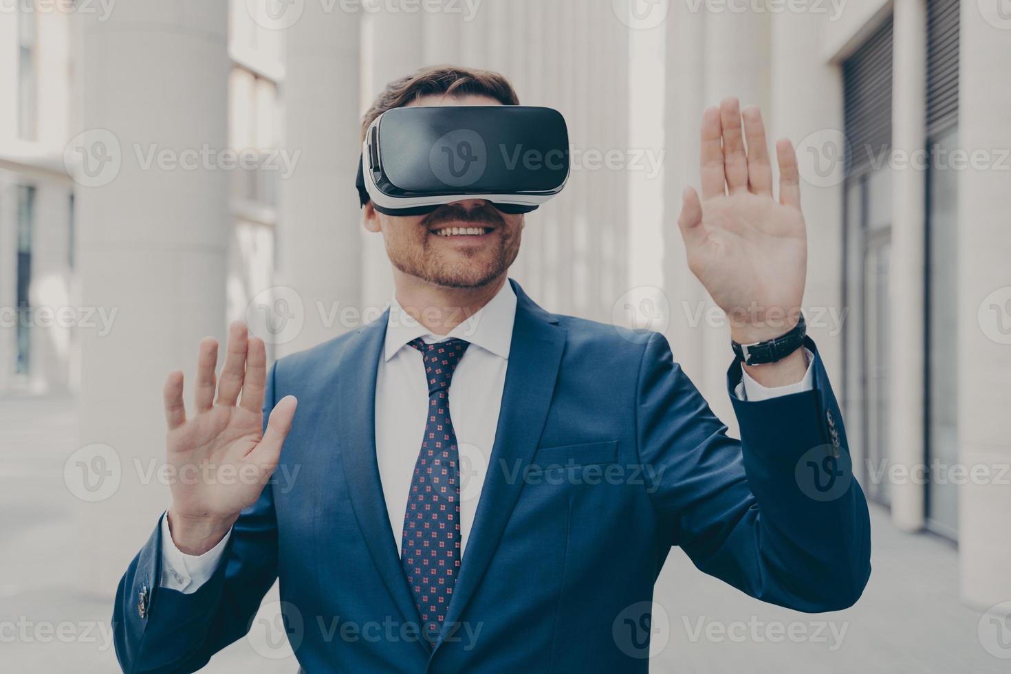 Businessman in suit trying out and experiencing virtual reality using mobile VR headset outdoors photo