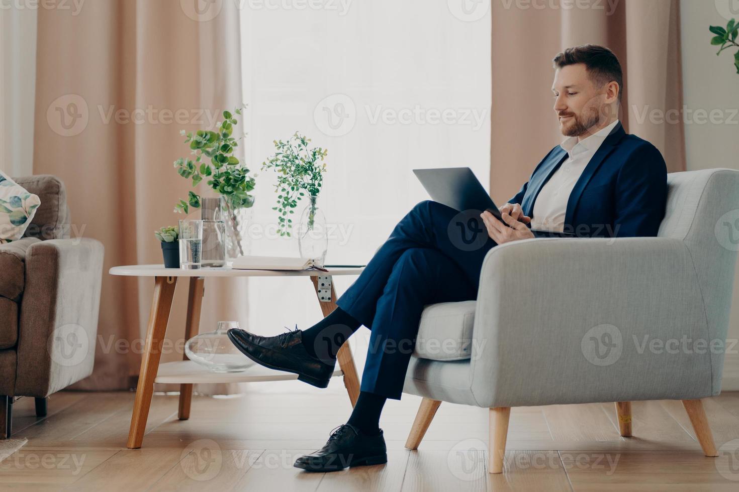 exitoso hombre de negocios con ropa formal se sienta en un cómodo sillón usa computadora