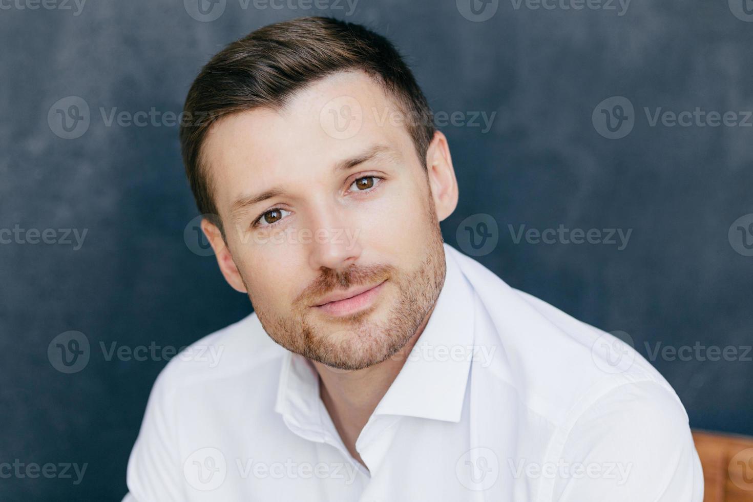 toma aislada de un apuesto joven trabajador corporativo vestido con una elegante camisa blanca, posa contra un fondo oscuro. hombre atractivo listo para una cita con su novia. concepto de personas y estilo de vida foto