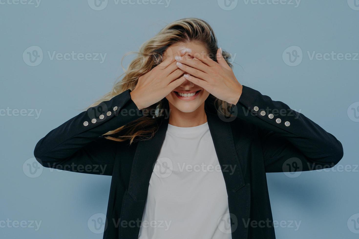 Happy blonde female covering her eyes with both hands and waiting to receive nice gift photo