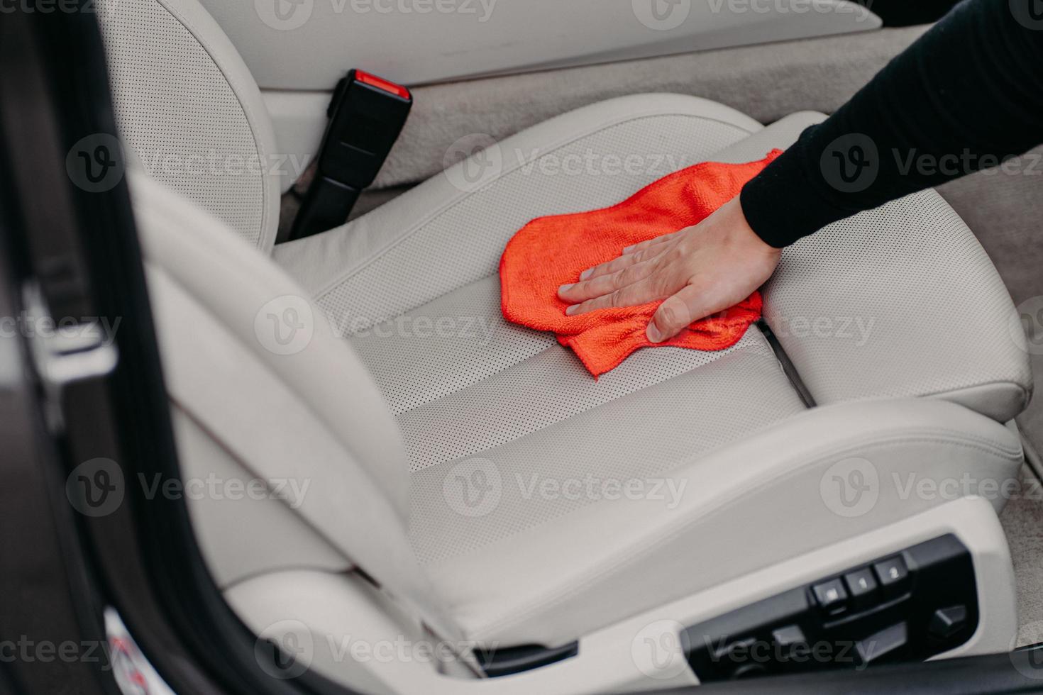 Close up shot of male worker cleans seat inside of car using microfibre cloth. Car detailing and valeting concept. Hand cleaning photo