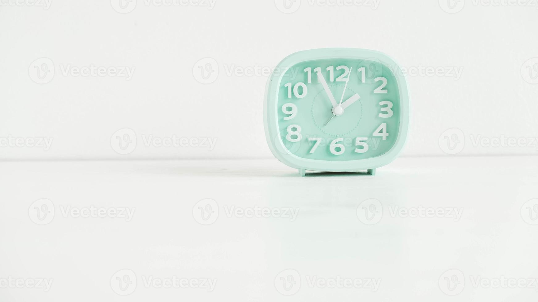 Blue table clock with arrows on a white table photo