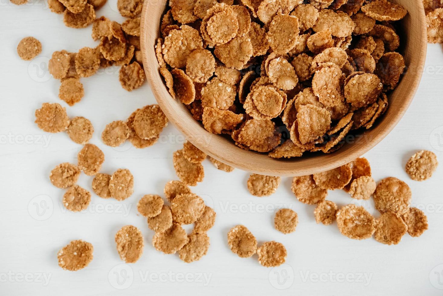 Crispy healthy dry cereal flakes in a wooden bowl on white background photo