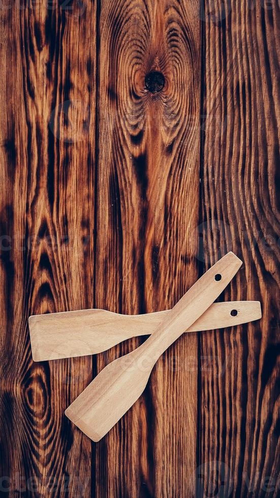 Wooden kitchen spatulas on brown table background photo