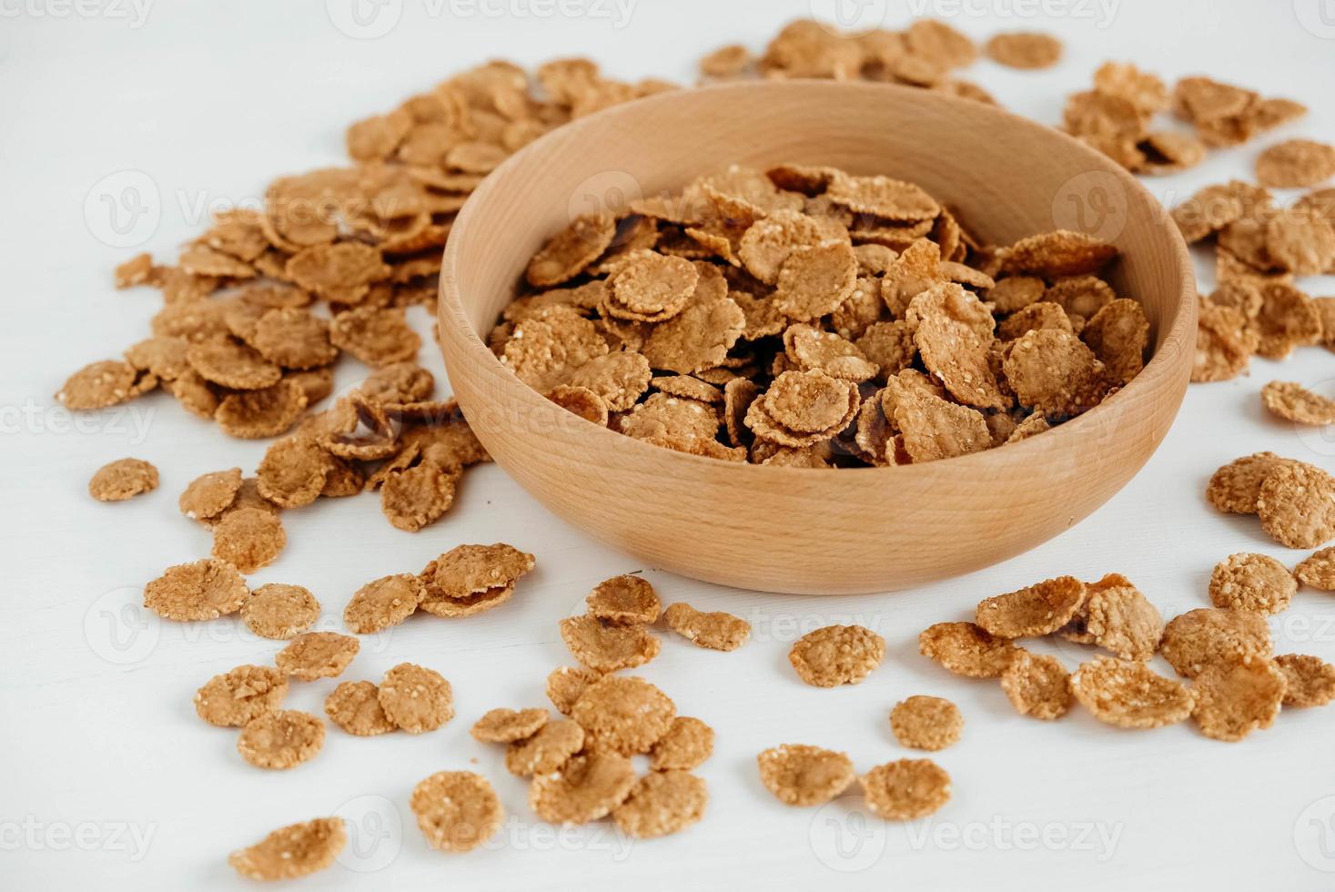 Crispy healthy dry cereal flakes in a wooden bowl on white background photo