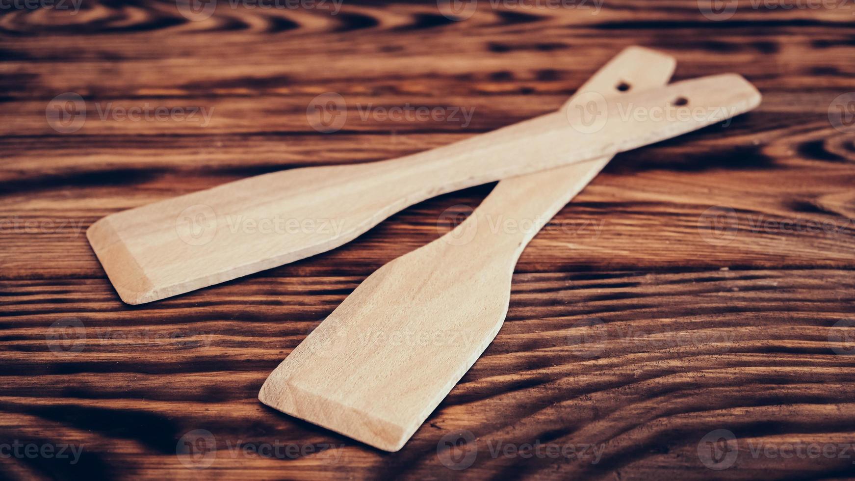 Wooden kitchen spatulas on brown table background photo